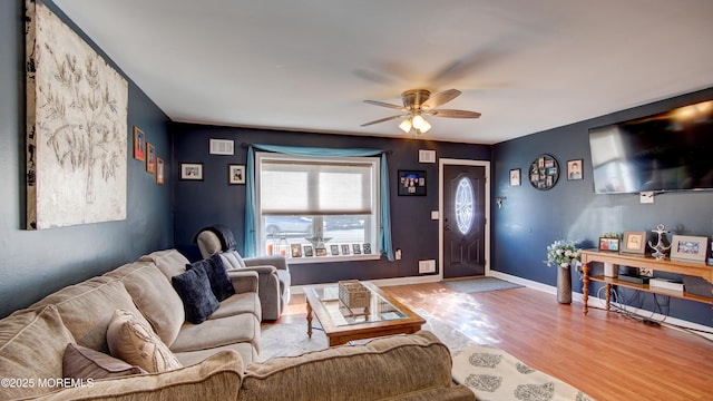 living room with a ceiling fan, visible vents, baseboards, and wood finished floors