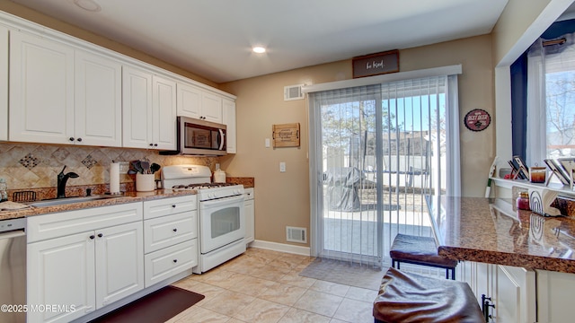 kitchen featuring appliances with stainless steel finishes, a sink, visible vents, and white cabinetry