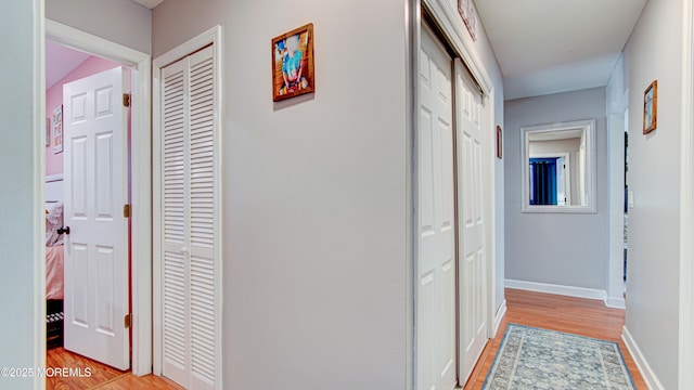 corridor featuring light wood-style flooring and baseboards