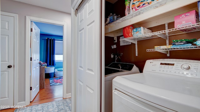 laundry room featuring laundry area, light wood-style flooring, and separate washer and dryer