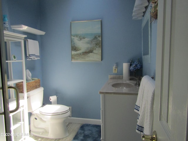 bathroom featuring toilet, baseboards, and vanity