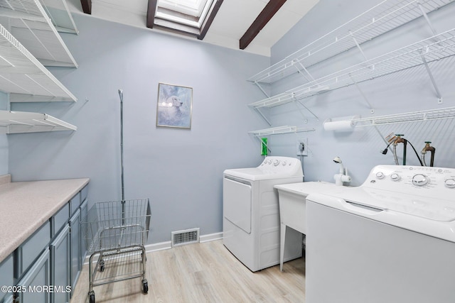 clothes washing area with laundry area, light wood finished floors, baseboards, visible vents, and separate washer and dryer