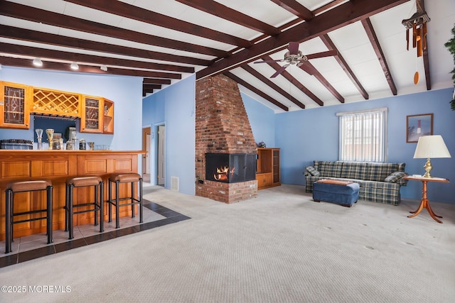 carpeted living area with a bar, a brick fireplace, lofted ceiling with beams, and a ceiling fan