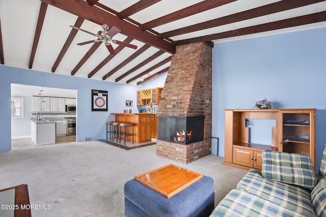 carpeted living room with vaulted ceiling with beams, a fireplace, visible vents, a sink, and ceiling fan