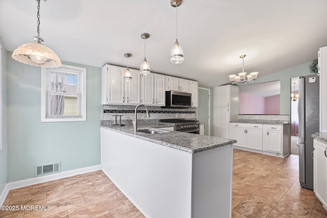 kitchen featuring a peninsula, appliances with stainless steel finishes, a sink, and visible vents