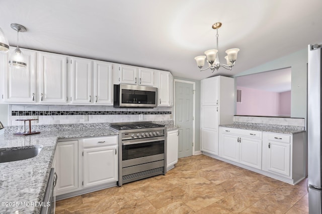 kitchen featuring decorative backsplash, appliances with stainless steel finishes, white cabinets, a sink, and light stone countertops