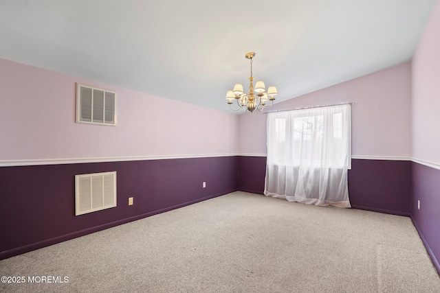 carpeted empty room featuring a chandelier, visible vents, and vaulted ceiling