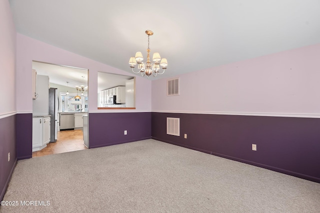 spare room with lofted ceiling, light carpet, visible vents, and an inviting chandelier