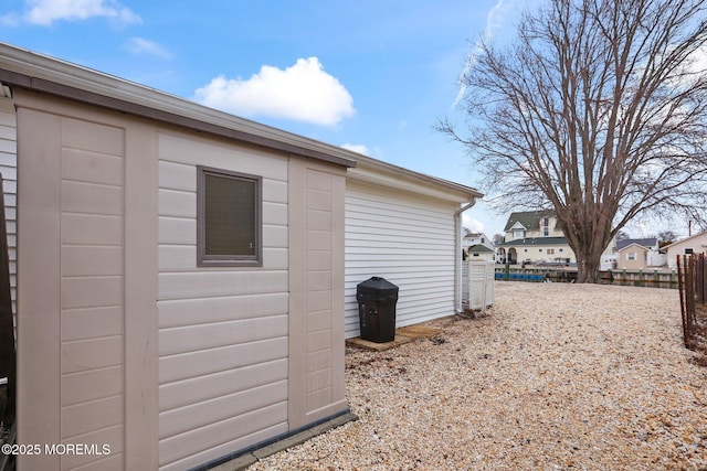 view of property exterior with a residential view, fence, and an outbuilding