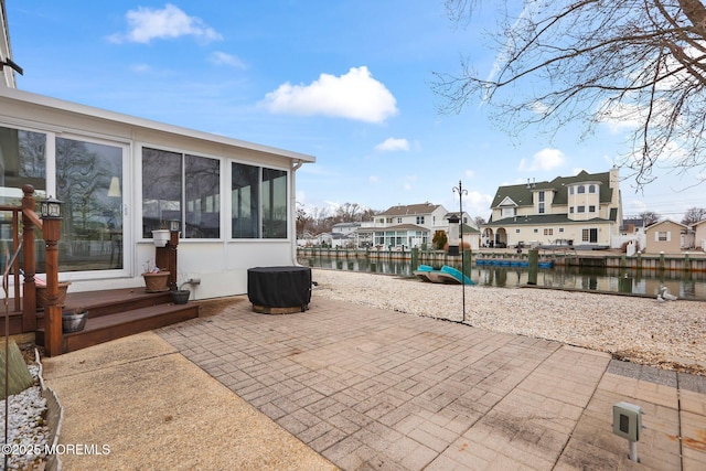 view of patio / terrace with a sunroom, a water view, and a residential view