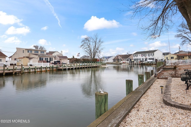 view of dock featuring a water view, fence, and a residential view