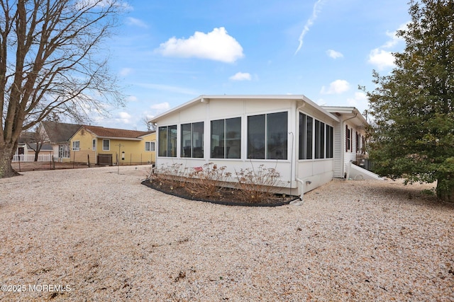 back of property with a sunroom and fence