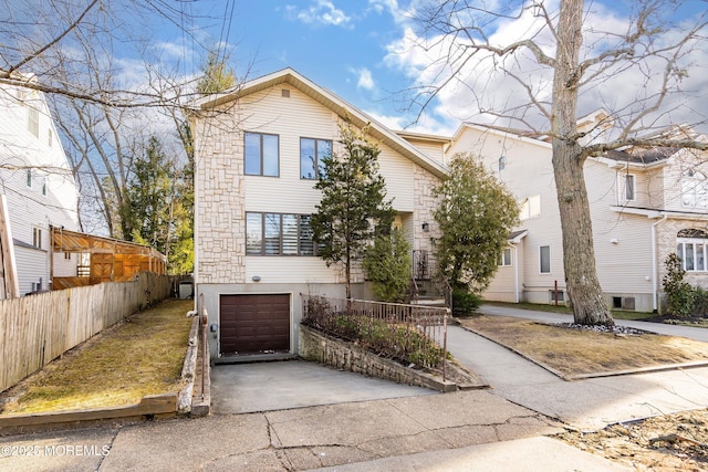 view of front facade with concrete driveway, a garage, and fence