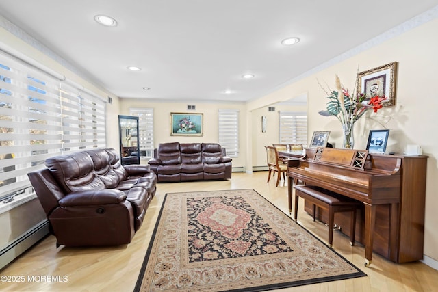 living area featuring a wealth of natural light, a baseboard heating unit, and light wood-style floors