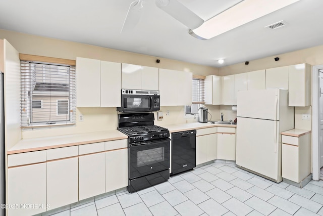 kitchen featuring visible vents, light countertops, light tile patterned flooring, white cabinets, and black appliances