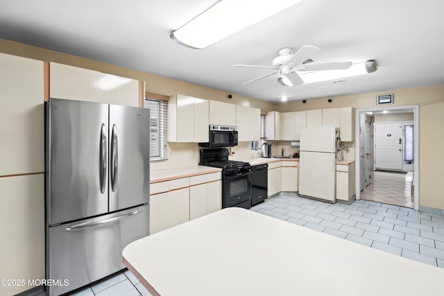 kitchen featuring light tile patterned floors, black appliances, white cabinets, and light countertops