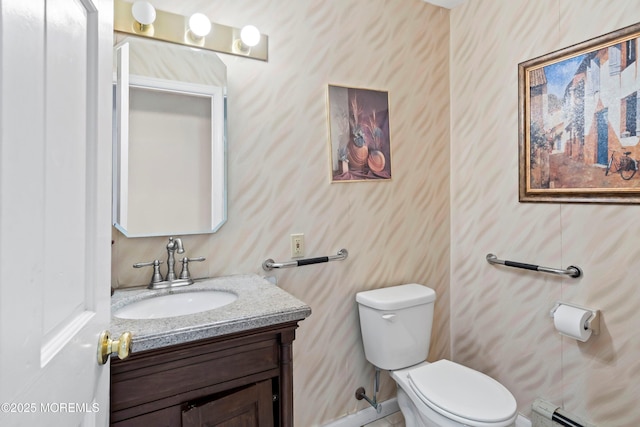 bathroom with vanity, baseboards, wallpapered walls, toilet, and baseboard heating