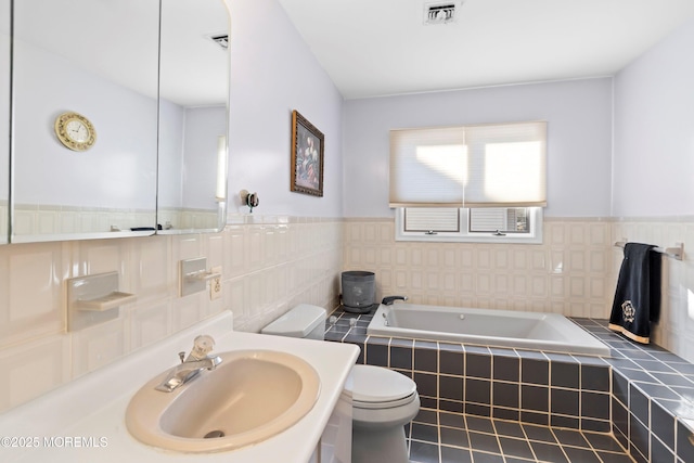 full bathroom with visible vents, toilet, a wainscoted wall, and a garden tub