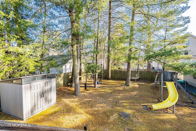 view of yard featuring an outbuilding, a playground, a fenced backyard, and a shed