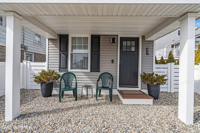 entrance to property featuring covered porch and fence