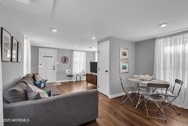 living area with dark wood-style floors, plenty of natural light, and baseboards