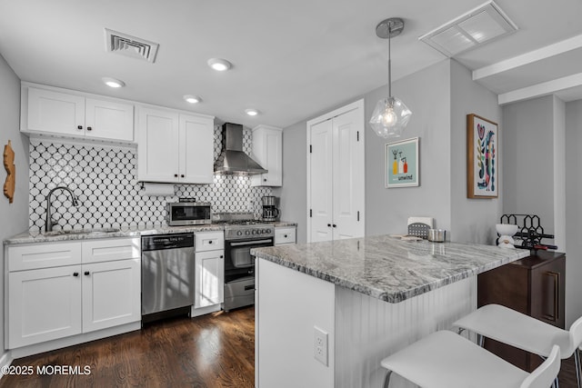 kitchen with wall chimney exhaust hood, visible vents, stainless steel appliances, and a sink