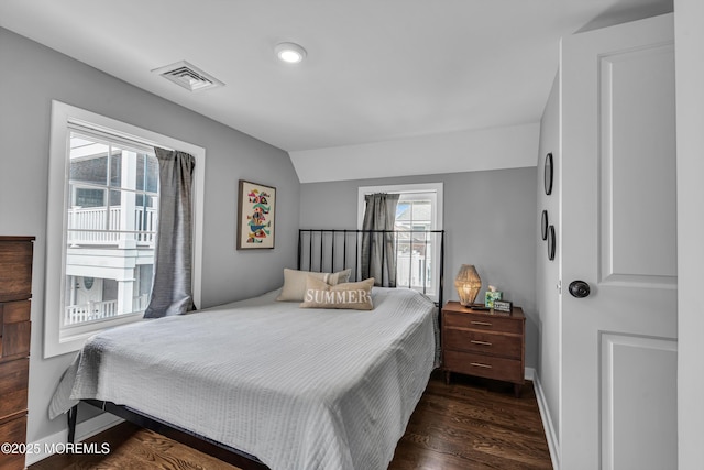 bedroom featuring dark wood-style floors, baseboards, visible vents, and vaulted ceiling