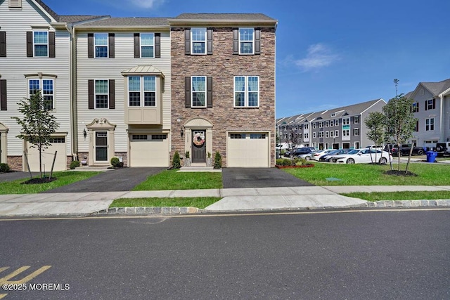 multi unit property featuring a garage, stone siding, and driveway