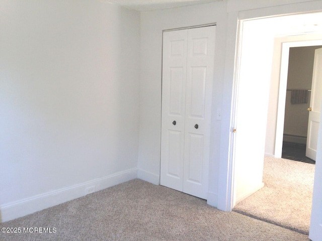 unfurnished bedroom with a closet, baseboards, and carpet flooring