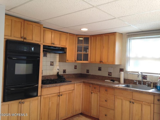 kitchen featuring a warming drawer, backsplash, a sink, black gas stovetop, and under cabinet range hood