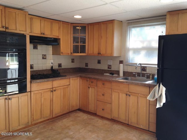 kitchen featuring black appliances, decorative backsplash, a sink, and under cabinet range hood