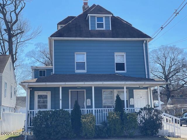 view of front of house with a porch, fence, and a chimney