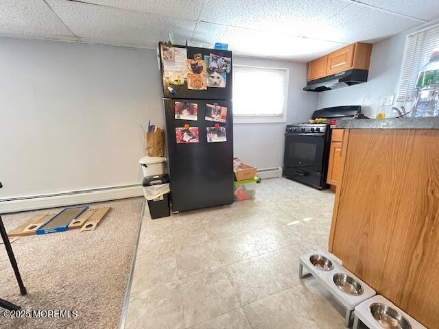 kitchen with a baseboard heating unit, black appliances, a drop ceiling, and under cabinet range hood