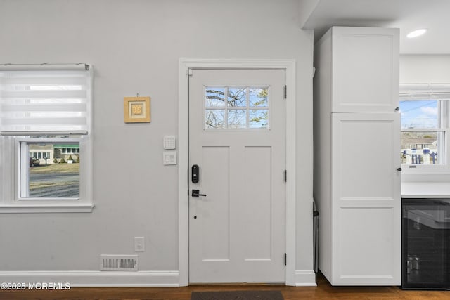 entrance foyer with wine cooler, visible vents, baseboards, and wood finished floors