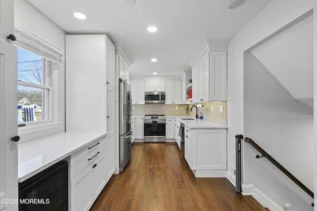 kitchen featuring stainless steel appliances, white cabinets, light countertops, and a sink