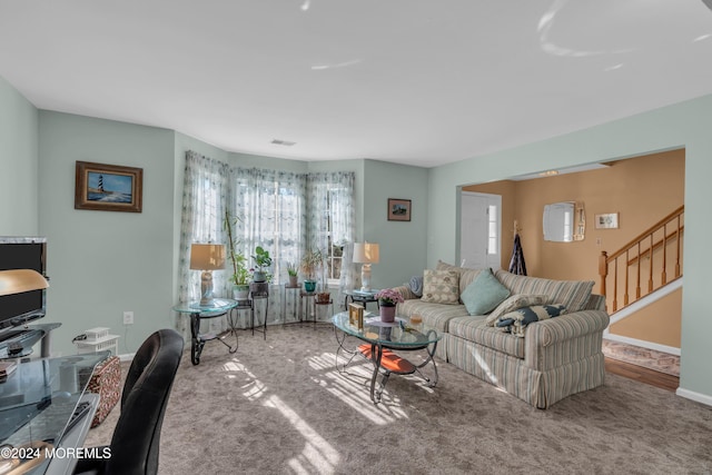 carpeted living area featuring stairs, visible vents, and baseboards