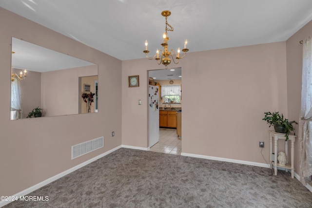 unfurnished dining area with a notable chandelier, light colored carpet, visible vents, a sink, and baseboards