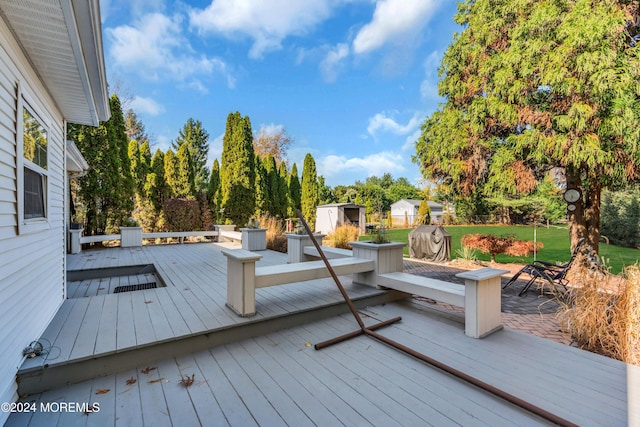 wooden terrace featuring an outbuilding and a shed