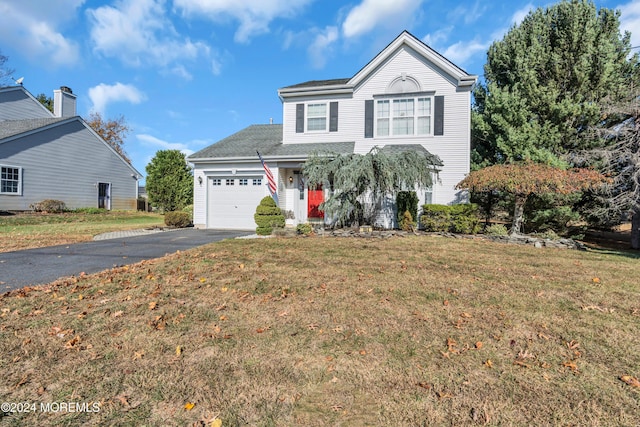 traditional-style home with driveway, a garage, and a front lawn