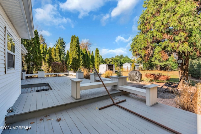 wooden deck featuring a storage unit and an outdoor structure