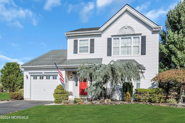 traditional-style home featuring a front yard, roof with shingles, driveway, and an attached garage