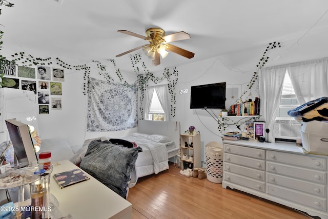 bedroom with light wood-type flooring, a ceiling fan, and cooling unit