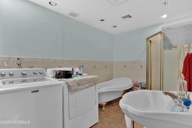 washroom with visible vents, light tile patterned floors, a sink, and washer / dryer