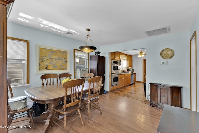 dining space with ceiling fan, light wood-style flooring, cooling unit, and visible vents