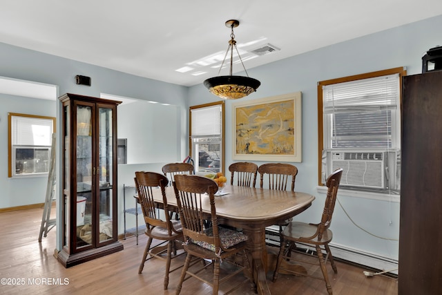 dining area with light wood-style floors, baseboards, visible vents, and cooling unit