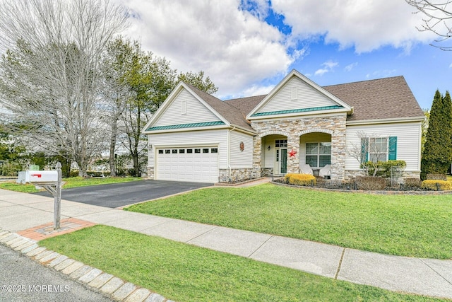 view of front facade with driveway, a garage, stone siding, roof with shingles, and a front yard