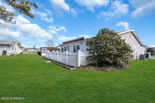 view of side of home featuring a yard, a residential view, central AC, and fence