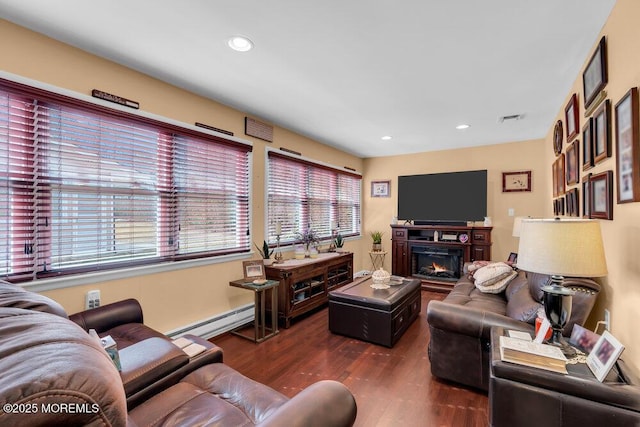 living area with a baseboard radiator, recessed lighting, visible vents, dark wood-type flooring, and a glass covered fireplace