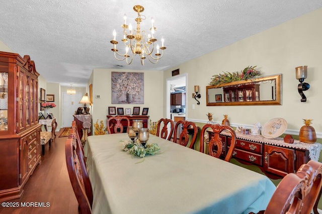 dining space with a textured ceiling, a chandelier, and dark wood-type flooring