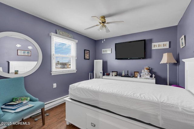 bedroom with a baseboard heating unit, ceiling fan, and wood finished floors